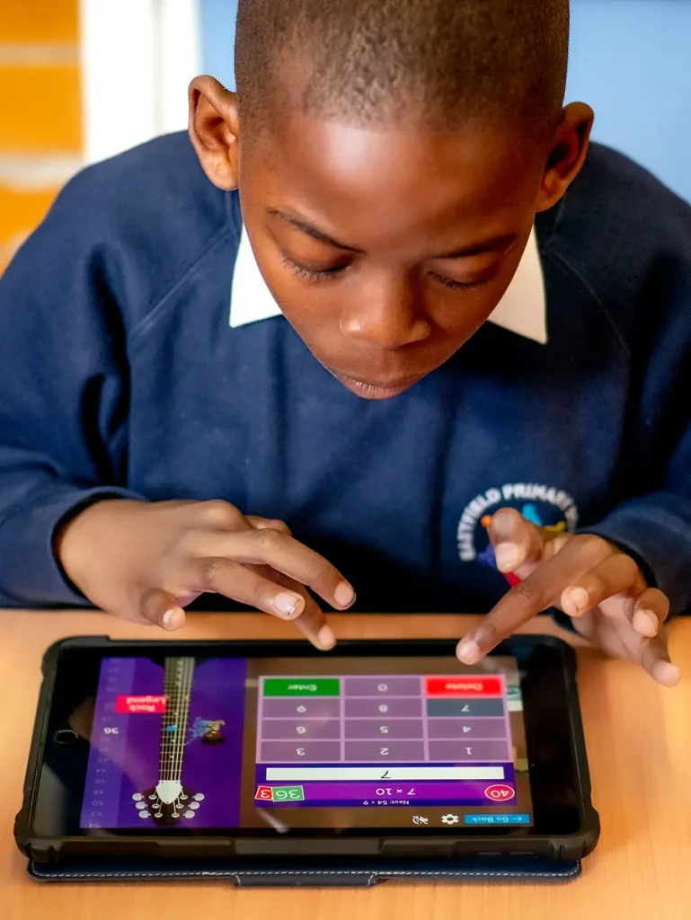 A boy playing timestable rockstars on a tablet